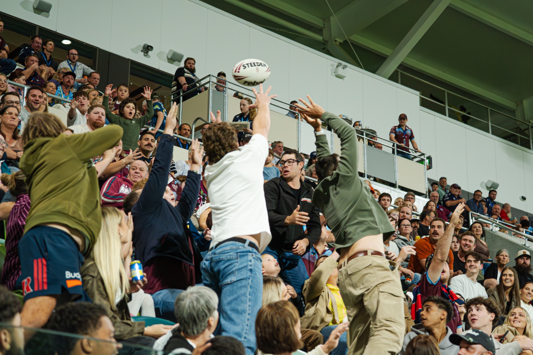 Fans reaching for a ball kicked into the crowd